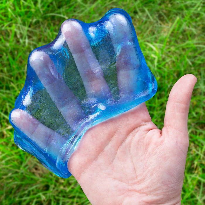 Hand holding a blue mold shaped like a hand against a grassy background
