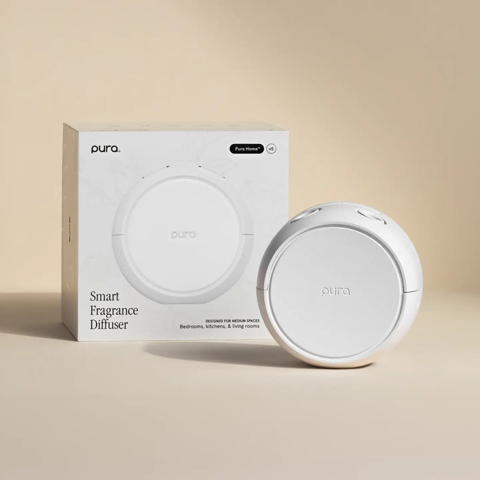 A white Pura Smart Fragrance Diffuser shown next to its white retail box on a warm beige background.