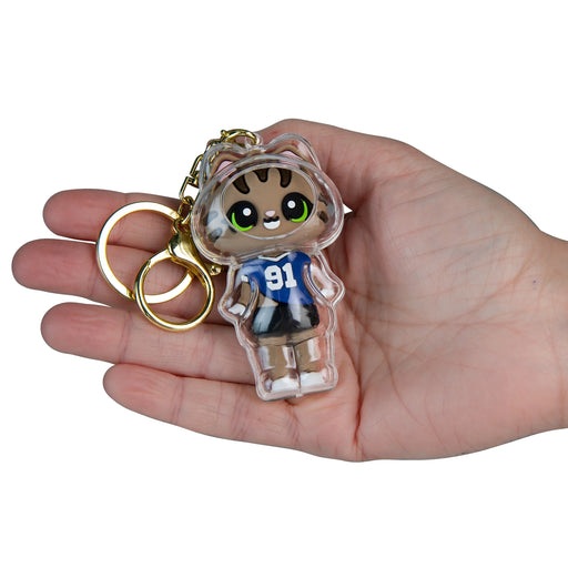 Hand holding a keychain with a cartoon character design on a white background