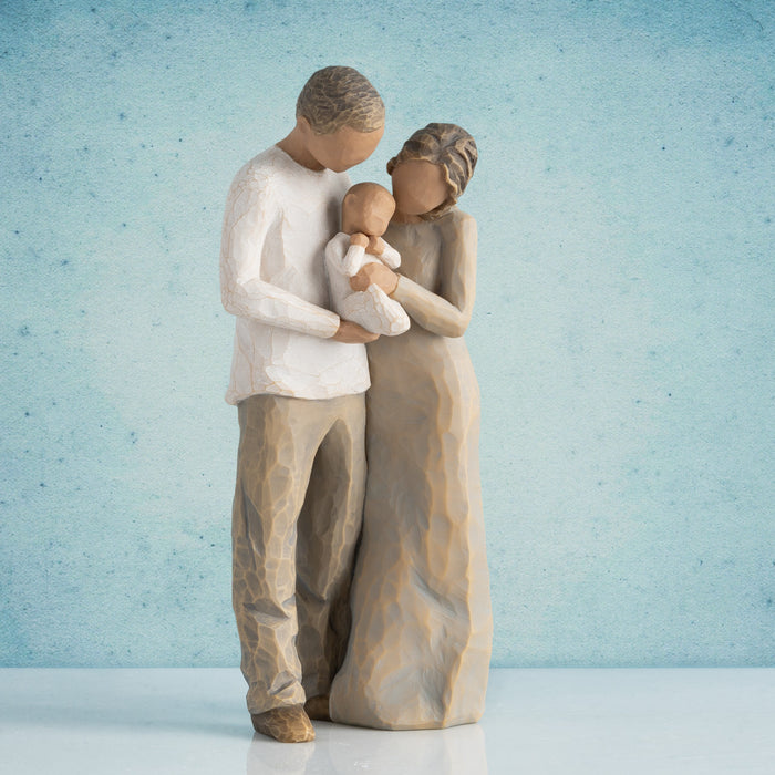Statue of a couple holding a baby against a light blue background