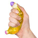A hand squeezing a translucent yellow sensory stress toy filled with glitter, featuring a purple textured top and a pink bottom, on a white background.