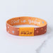 Wristband with 'God is good' text and prayer prompt on a marble surface