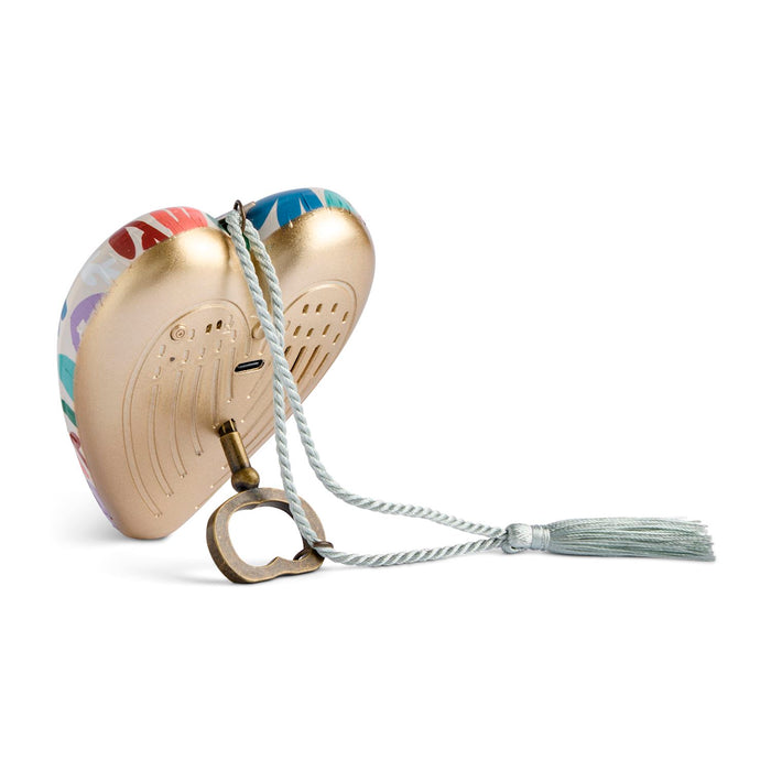 A heart-shaped metal wind instrument case with a gold-toned finish, multicolor patterned edges, a white braided hanging cord, metal ring, and tassel, shown on a white background.