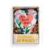A heart-shaped keepsake ornament presented in a gift box. The ornament has a white base with colorful floral patterns in purple, blue, green, and orange, featuring a large coral-pink heart in the center with the words 'one loved mom' in black script.