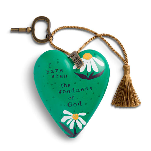 A green heart-shaped wooden prayer tag with white daisy illustrations and the printed text 'I have seen the goodness of God'. It features a brass keyhole loop at the top, a gold-colored hanging cord, and a matching tassel.