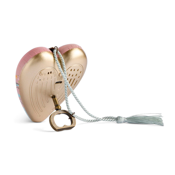 A heart-shaped angel wing clutch purse in metallic gold and pink, featuring a white braided strap with a tassel and a brass bottle opener.
