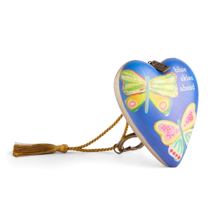 Heart-shaped object with butterfly designs and 'blue skies ahead' text on a white background