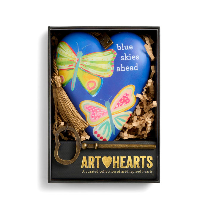 Heart-shaped blue plaque with butterfly designs and 'blue skies ahead' text, featuring 'Art Hearts' branding.