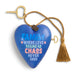 A blue heart-shaped wall hanging ornament with a rope tassel and keyhole detail, featuring the text 'FAMILY WHERE LOVE BEGINS AS CHAOS NEVER ENDS' in blue, pink, and white lettering, shown on a white background.