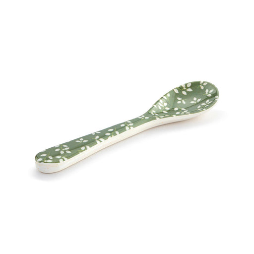 Green ceramic spoon with white floral pattern on a white background