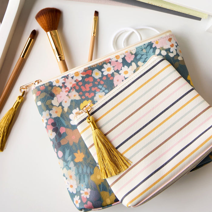Floral pouch with tassel and striped pouch on a white surface with makeup brushes.