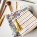 Floral pouch with tassel and striped pouch on a white surface with makeup brushes.