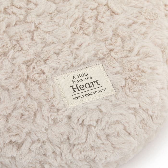 Close-up of a textured beige blanket with a label reading 'A Hug from the Heart' on a white background.