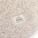 Close-up of a textured beige blanket with a label reading 'A Hug from the Heart' on a white background.