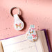 Butterfly-patterned keychain on a pink textured background with an open book.