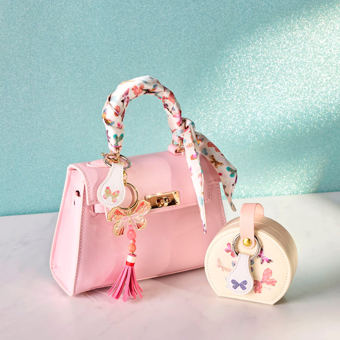 Pink handbag with decorative accessories on a light blue background