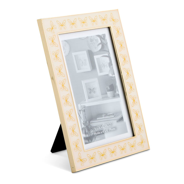 A cream-colored picture frame with a gold butterfly border pattern, shown standing on a black easel against a white background.