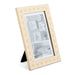 A cream-colored picture frame with a gold butterfly border pattern, shown standing on a black easel against a white background.
