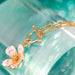 Gold bracelet with a floral charm on a light blue background