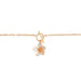 Gold bracelet with a floral charm on a white background