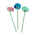 Three colorful ceramic flowers on green stems against a white background