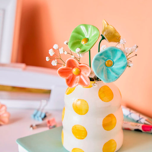 Colorful ceramic vase with polka dots and decorative flowers on a blurred background