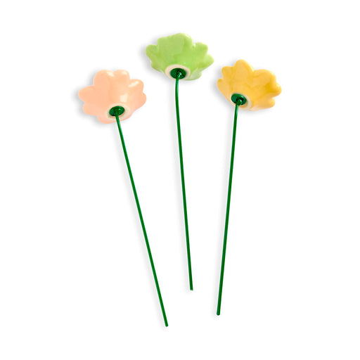 Three floral-shaped hairpins in peach, green, and yellow on a white background
