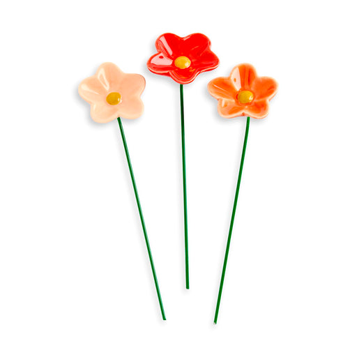 Three ceramic flowers in red, orange, and pink on a white background