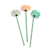 Three ceramic flowers on green stems against a white background