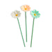 Three colorful ceramic flowers on green stems against a white background
