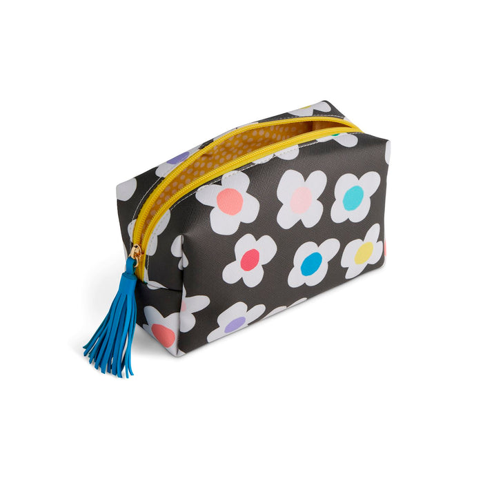 A rectangular cosmetic pouch with a black background and a white daisy pattern featuring multicolored centers. It has a bright yellow zipper, a blue tassel zipper pull, and a gold-tone metal zipper pull.
