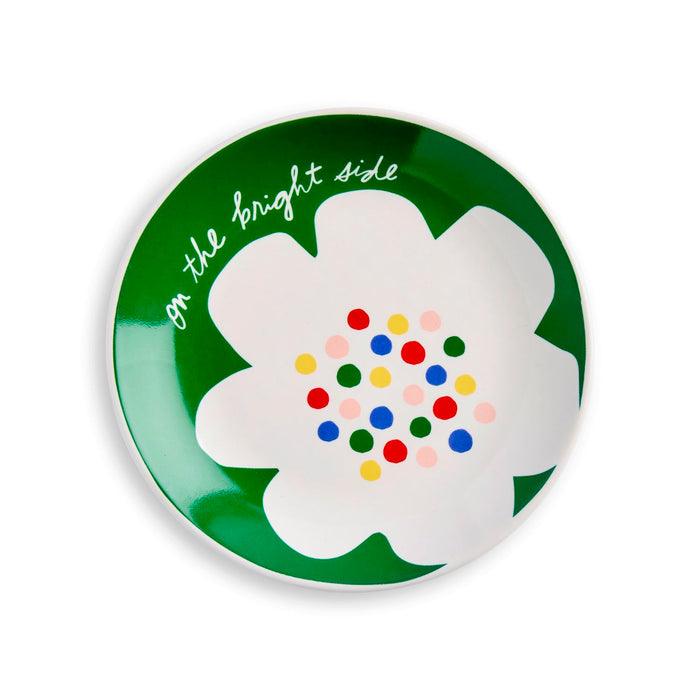 Round green plate with a white flower design and colorful centers, featuring the text 'On the bright side'.