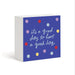 A square decorative block sign with a white side and a blue front panel. The front features the phrase 'its a good day to have a good day' in white script, surrounded by scattered pastel and bright polka dots in red, yellow, light blue, and lavender.