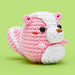 Crocheted pink and white animal toy on a green background