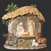 Nativity scene figurine with stable, figures, and animals on a dark background