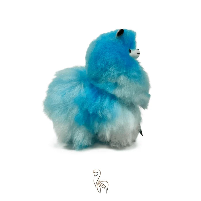 A fluffy faux-fur alpaca plush toy in a vibrant blue and white gradient, sitting on a solid white background with a small stylized logo below.