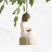 Decorative figurine of a woman holding a book with a hanging element, on a white background.