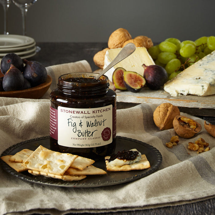 Stonewall Kitchen Fig & Walnut Butter jar on a platter with crackers, figs, and cheese.