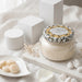 Decorative candle with leopard print packaging on a marble surface with a neutral background