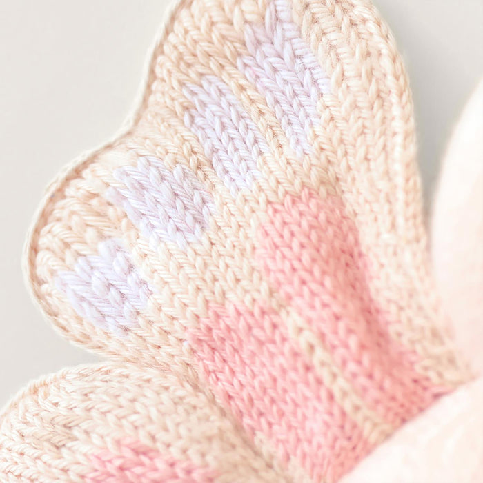 Close-up of a knitted fabric with pink and beige colors on a light background