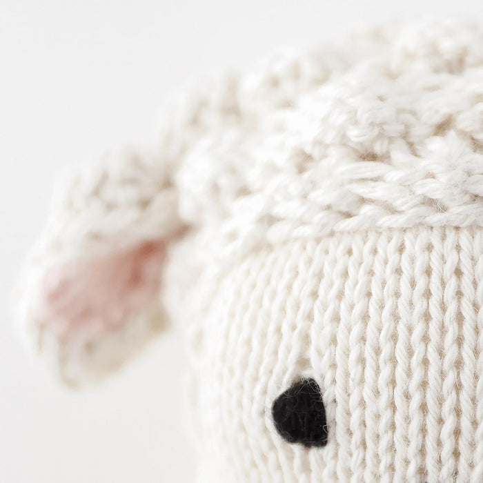 Close-up of a knitted white bunny with a black nose on a light background