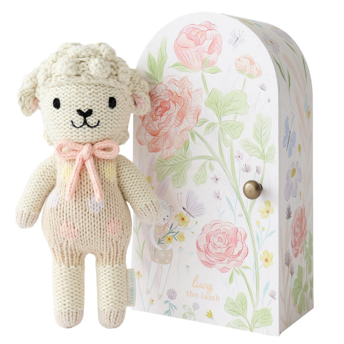 Knitted lamb toy with a floral-patterned box on a white background