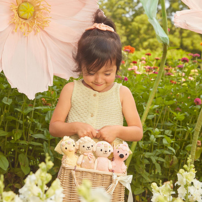 Young girl holding a basket of teddy bears in a garden setting