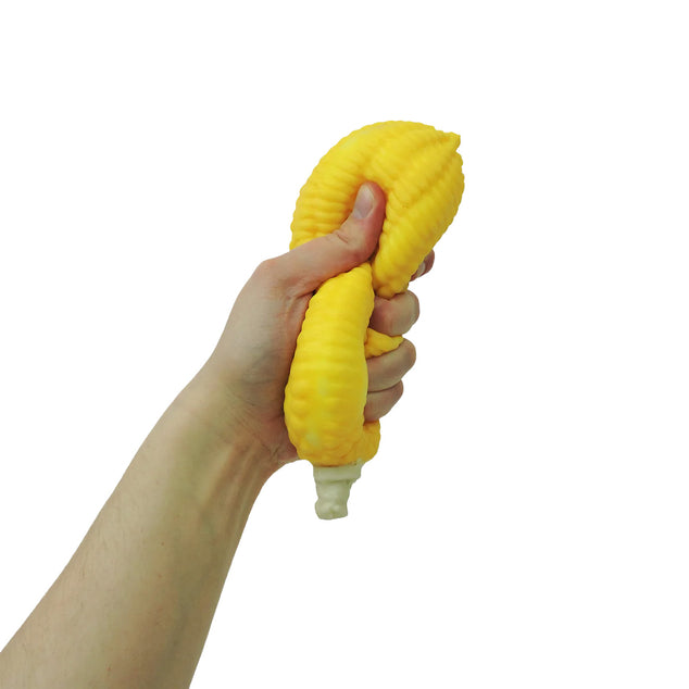 Hand holding a yellow corn-shaped object against a white background