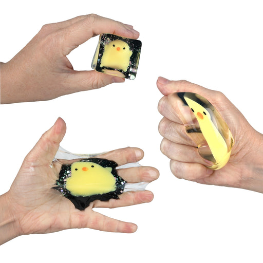 Hands holding small square toys with chick designs on a white background