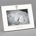 Silver photo frame with 'Baptism' engraving and a cross charm, containing a black and white photo of baby shoes.
