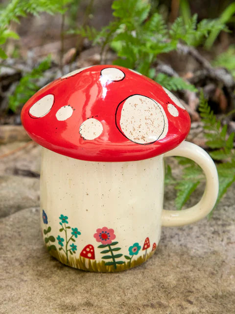Mushroom-shaped mug with a red cap and white spots, featuring floral designs on a natural background.