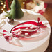 Decorative candy cane with peppermints on a white surface with a festive background.