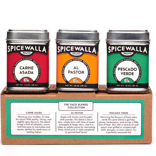 Three Spicewalla spice tins on a cardboard stand with labels for Carne Asada, Al Pastor, and Pescado Verde.