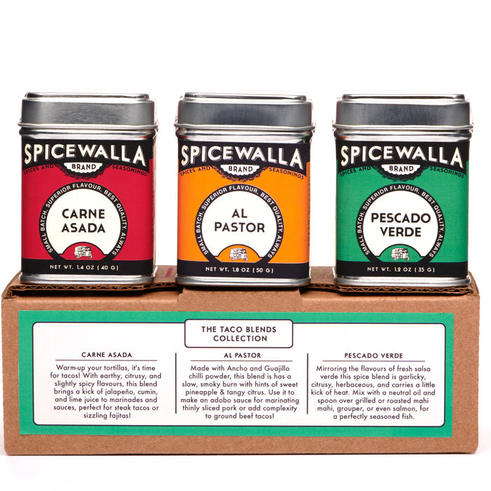 Three Spicewalla spice tins on a cardboard stand with labels for Carne Asada, Al Pastor, and Pescado Verde.